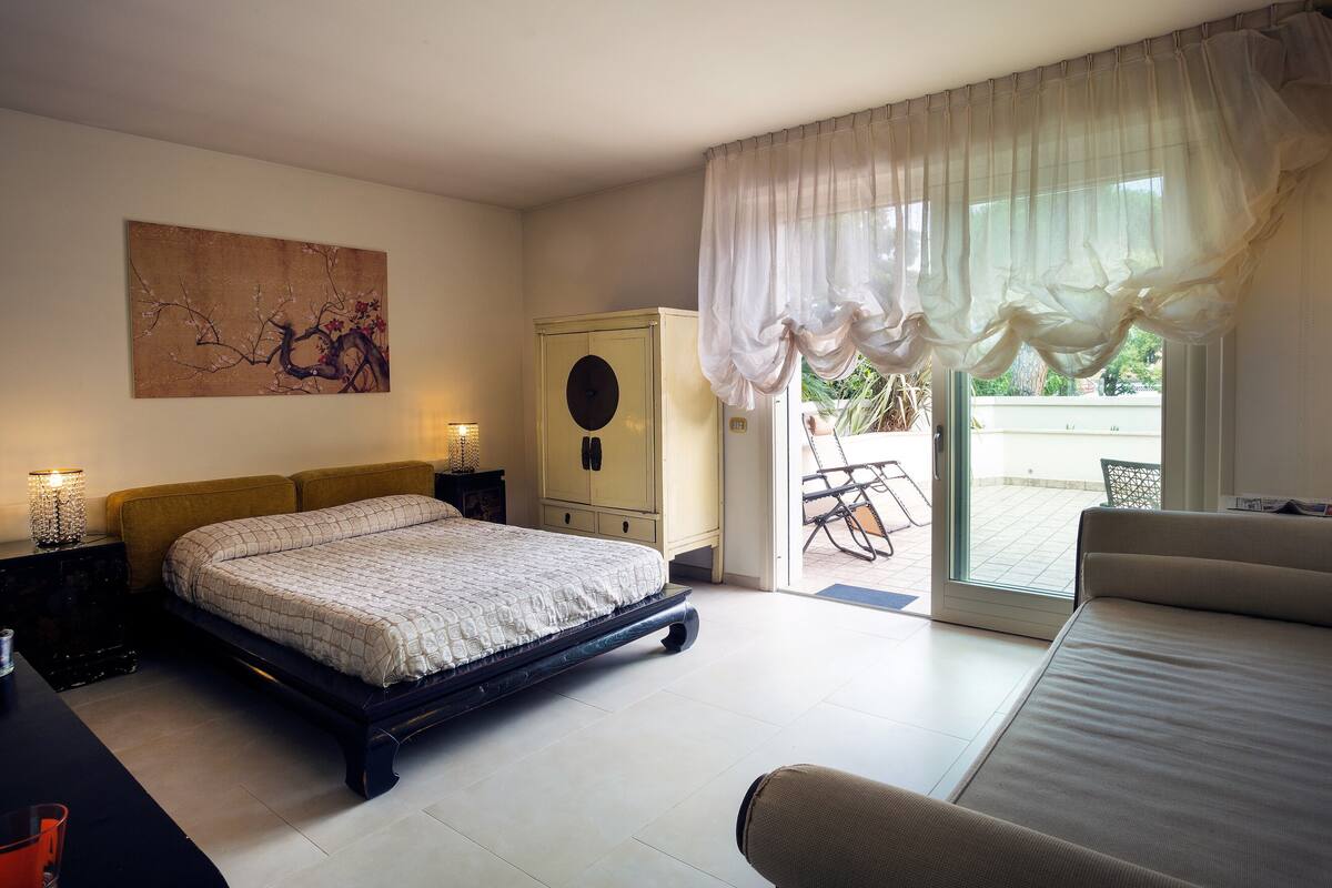 Une chambre à coucher comprenant un lit, une table de chevet, une armoire et donnant sur l’extérieur.