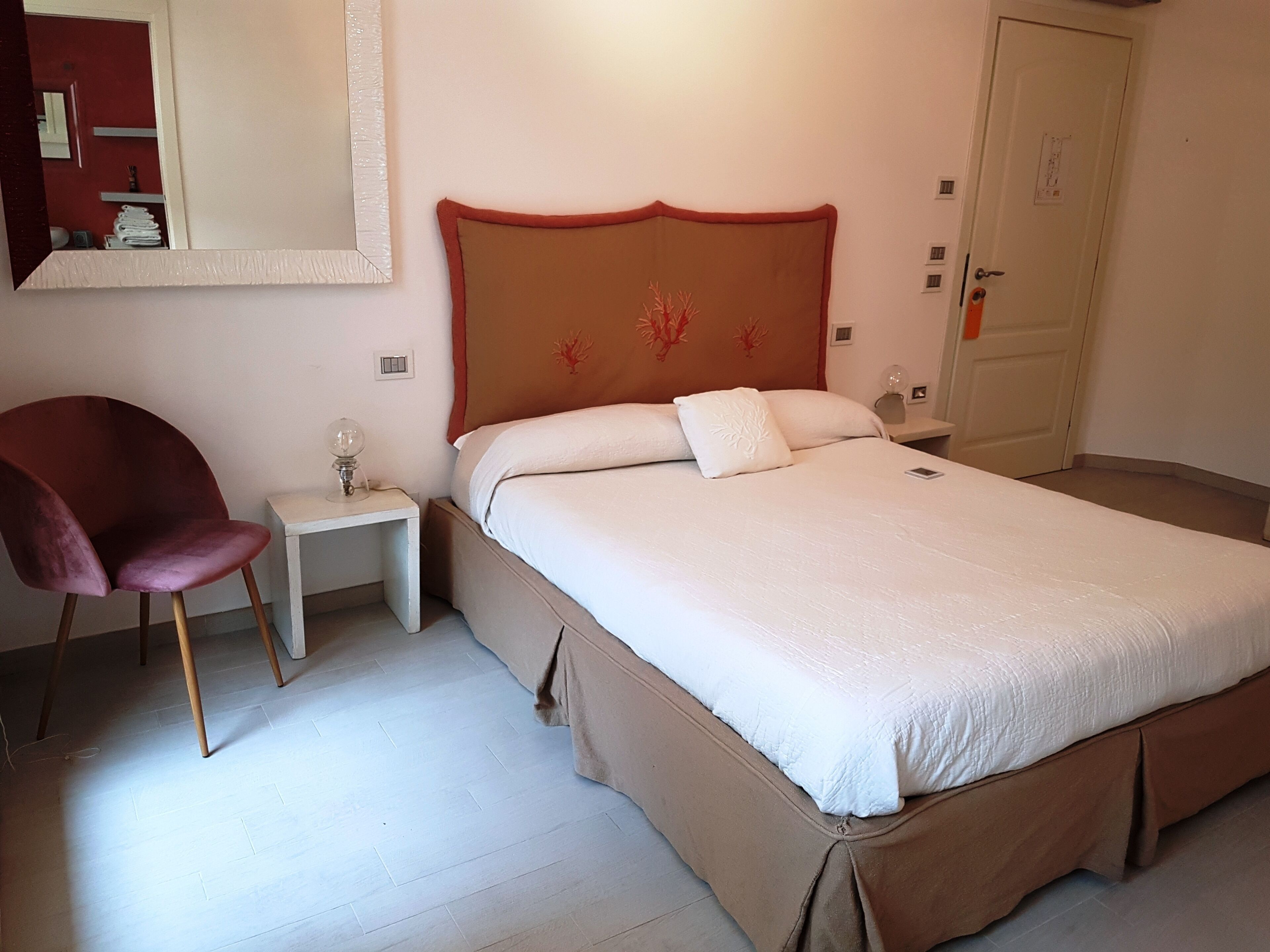 Una camera da letto con un letto grande, un comodino, una sedia e una porta.
