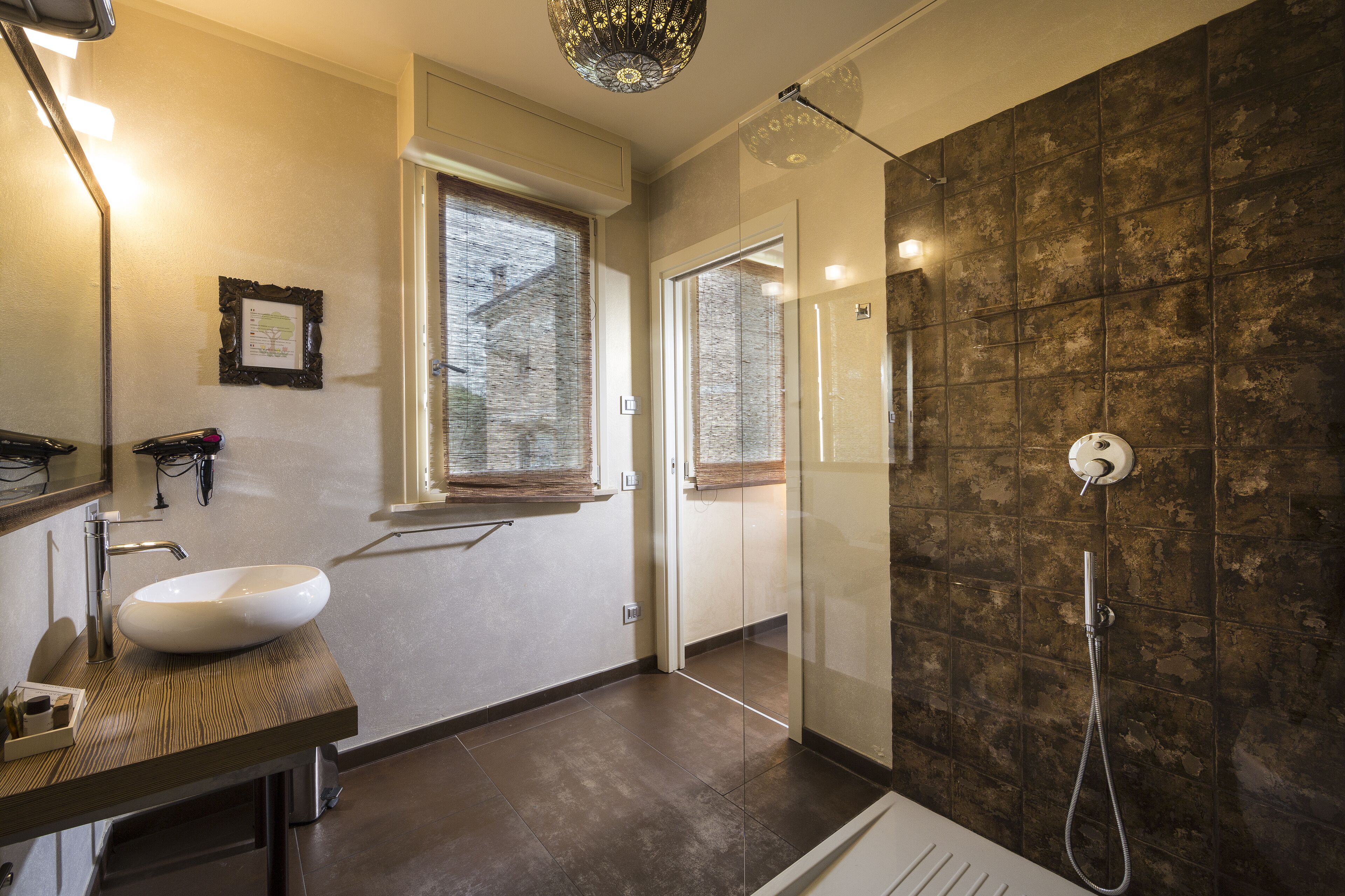 A modern bathroom with a large sink, a glass shower enclosure, and a window providing natural light.