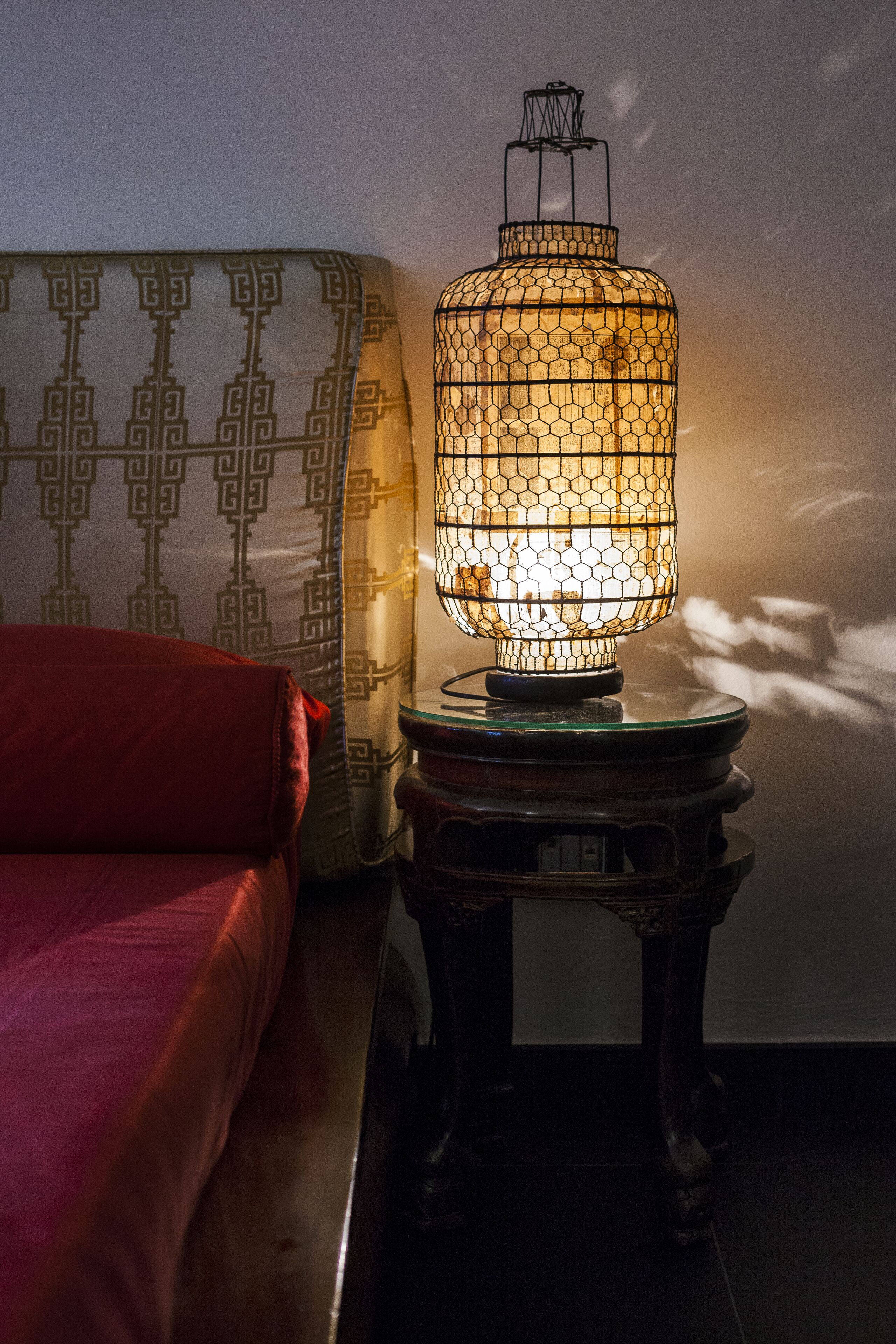 Ein Zimmer mit Wandmuster, einem roten Sofa und einem Tisch mit einer dekorativen Lampe.