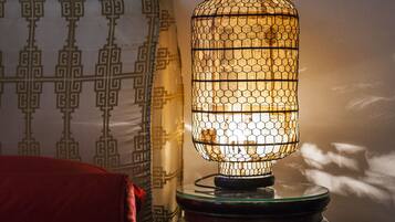 Ein Zimmer mit Wandmuster, einem roten Sofa und einem Tisch mit einer dekorativen Lampe.