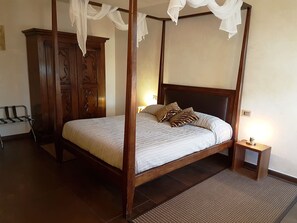 A four-poster bed with a wooden frame and white bedding, a nightstand with a lamp, and a wooden wardrobe. - La Villa Desenzano (Desenzano del Garda)