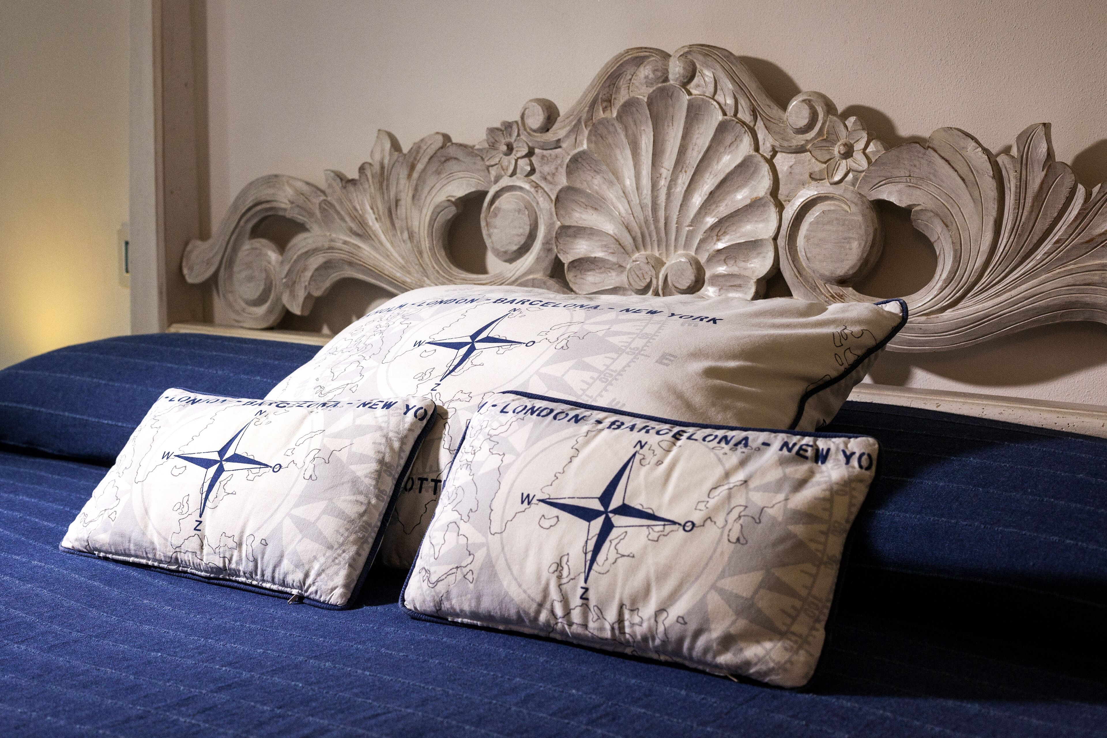 A bed with a decorative headboard and two pillows with a compass design.
