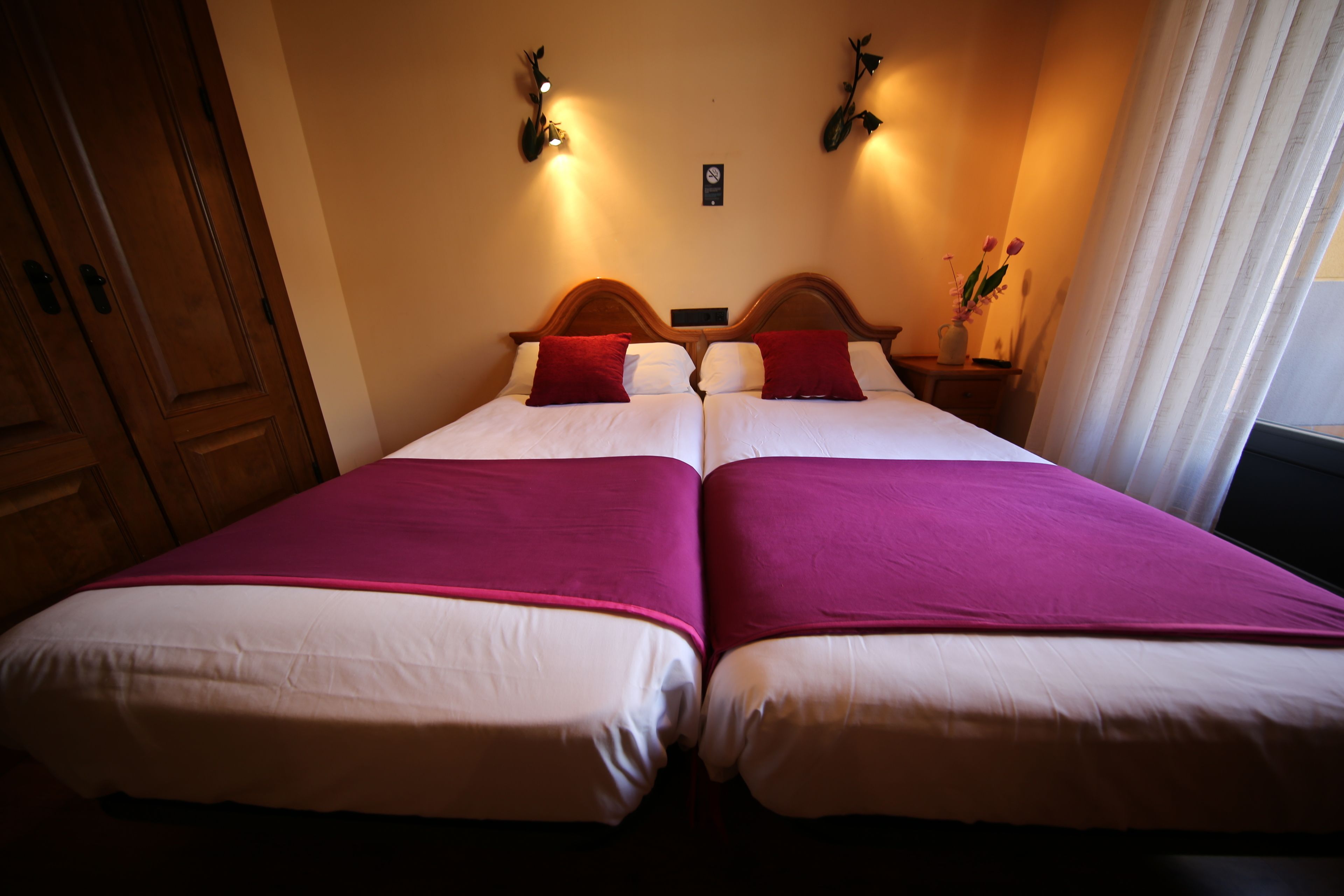 A double bed with a wooden headboard, two bedside tables, and a vase with flowers.