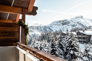 Un balcón de madera con vistas a montañas nevadas y un albergue.