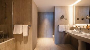 A modern bathroom with a walk-in shower, a large sink, and a mirror.
