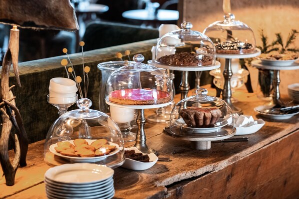 Un bufé con diversos postres bajo campanas de cristal, incluyendo pasteles y repostería.