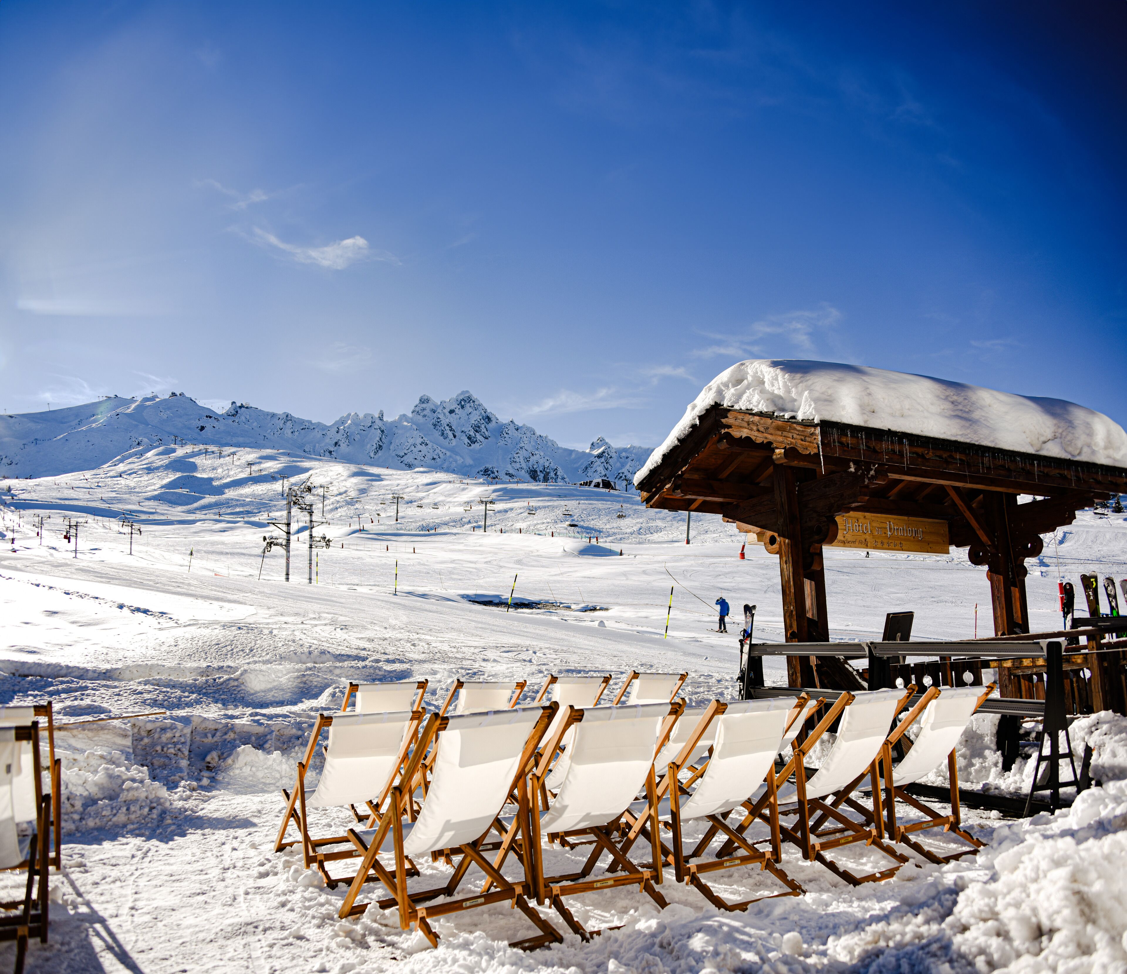 A ski resort with a wooden chalet, ski lifts, and snow-covered chairs.