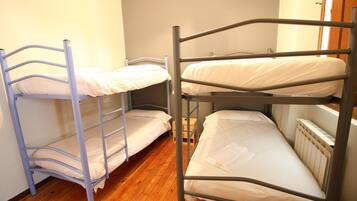 Three comfortable beds with mattresses and pillows are arranged in a row in this dormitory-style room.