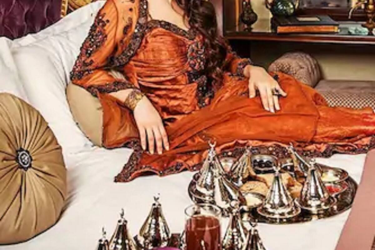 A room with a bed, ornate furniture, and a view of a cityscape.