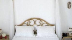 Een bed met hemelbed, twee nachtkastjes en een wandlamp.