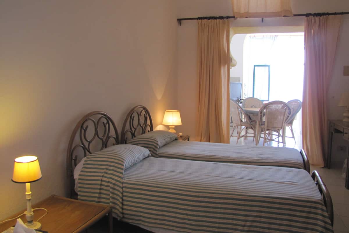 Une chambre d’hôtel avec deux lits, une table de chevet avec une lampe, une chaise et une vue sur l’extérieur.
