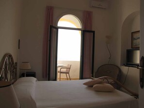 A hotel room with a bed, a chair, a TV, and a balcony with curtains. - Hotel Casa Del Sole (Serrara Fontana)