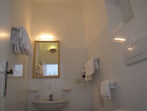 Een badkamer met een wastafel, spiegel en meerdere handdoeken aan de wand.