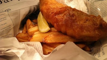 A meal of fish and chips with a lemon wedge, served on a paper with printed text.
