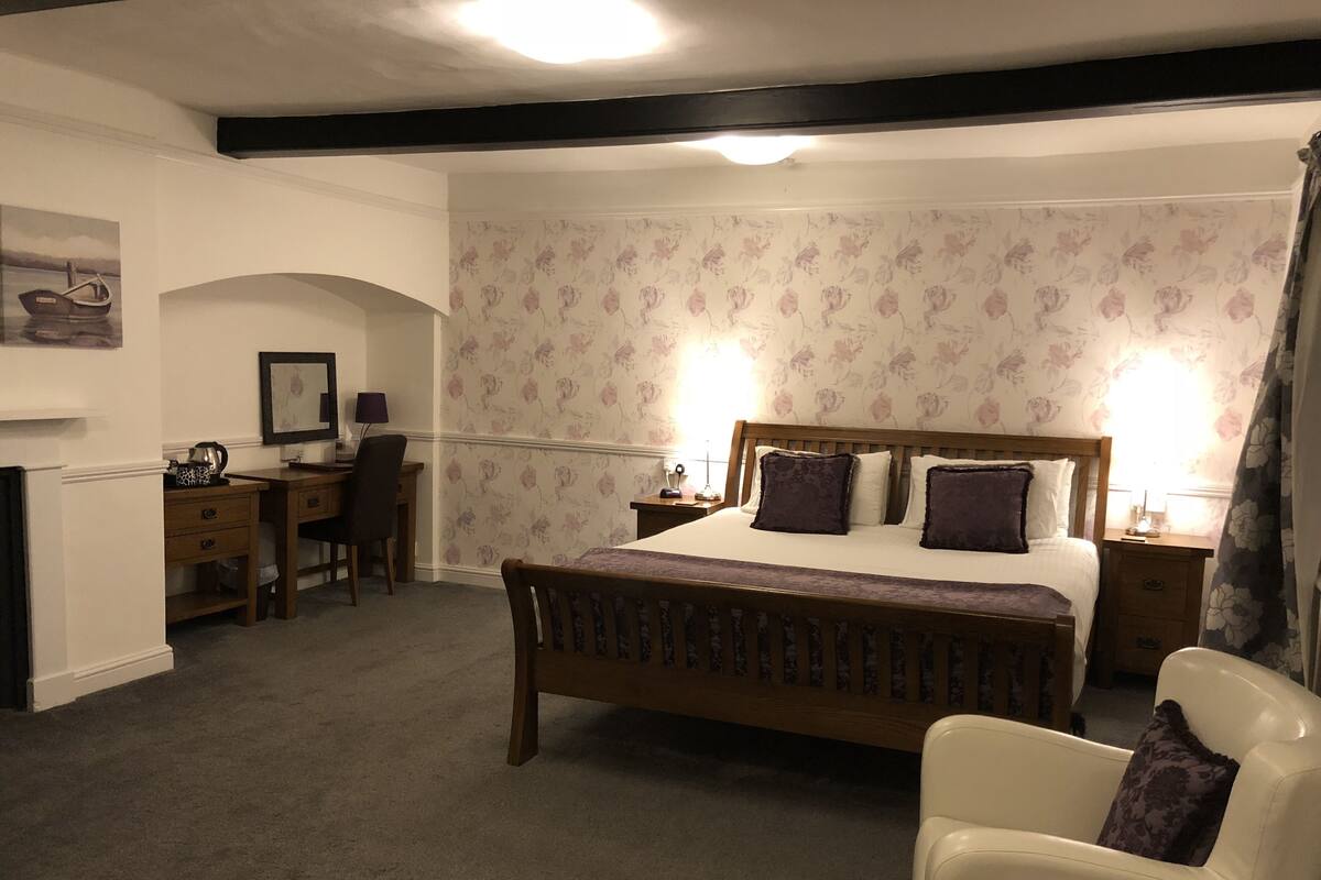A bedroom with a bed, a desk, a chair, and a nightstand.