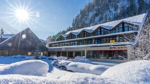 Un hôtel dont le toit est recouvert de neige et qui possède de nombreuses fenêtres, entouré de neige et de montagnes.