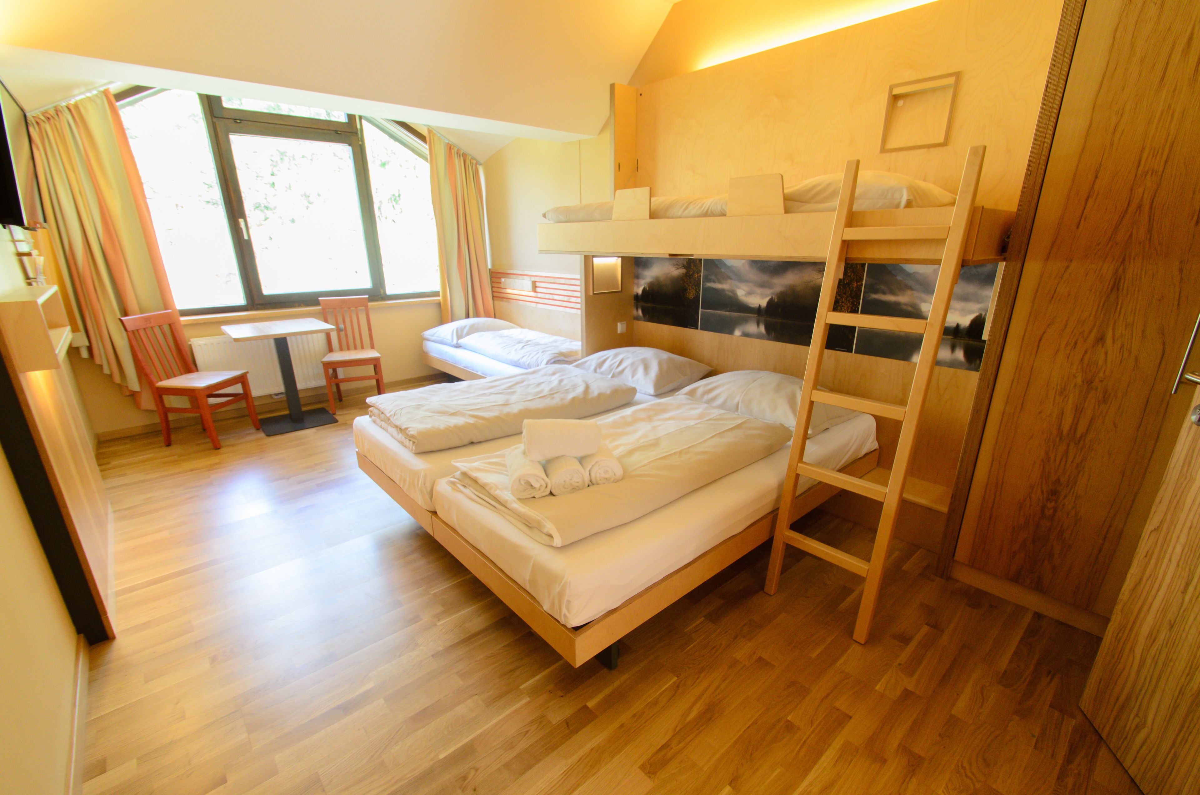 A room with two bunk beds, a wooden desk, and a chair.