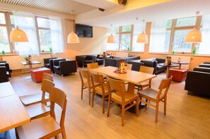 Enjoy dining and socializing in this spacious dining area with a long table, comfortable seating, and a flat-screen TV.