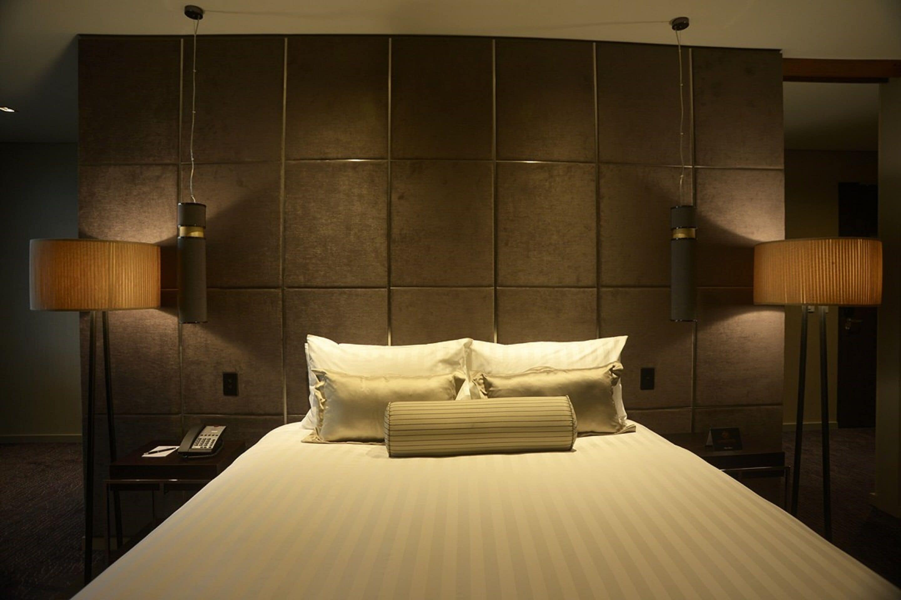 A hotel room with a large bed, two bedside lamps, and a modern headboard.