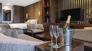 A modern hotel room with a large bed, a sofa, a TV, and a minibar with champagne glasses. - The Beetson Hotel (Petrie Terrace)