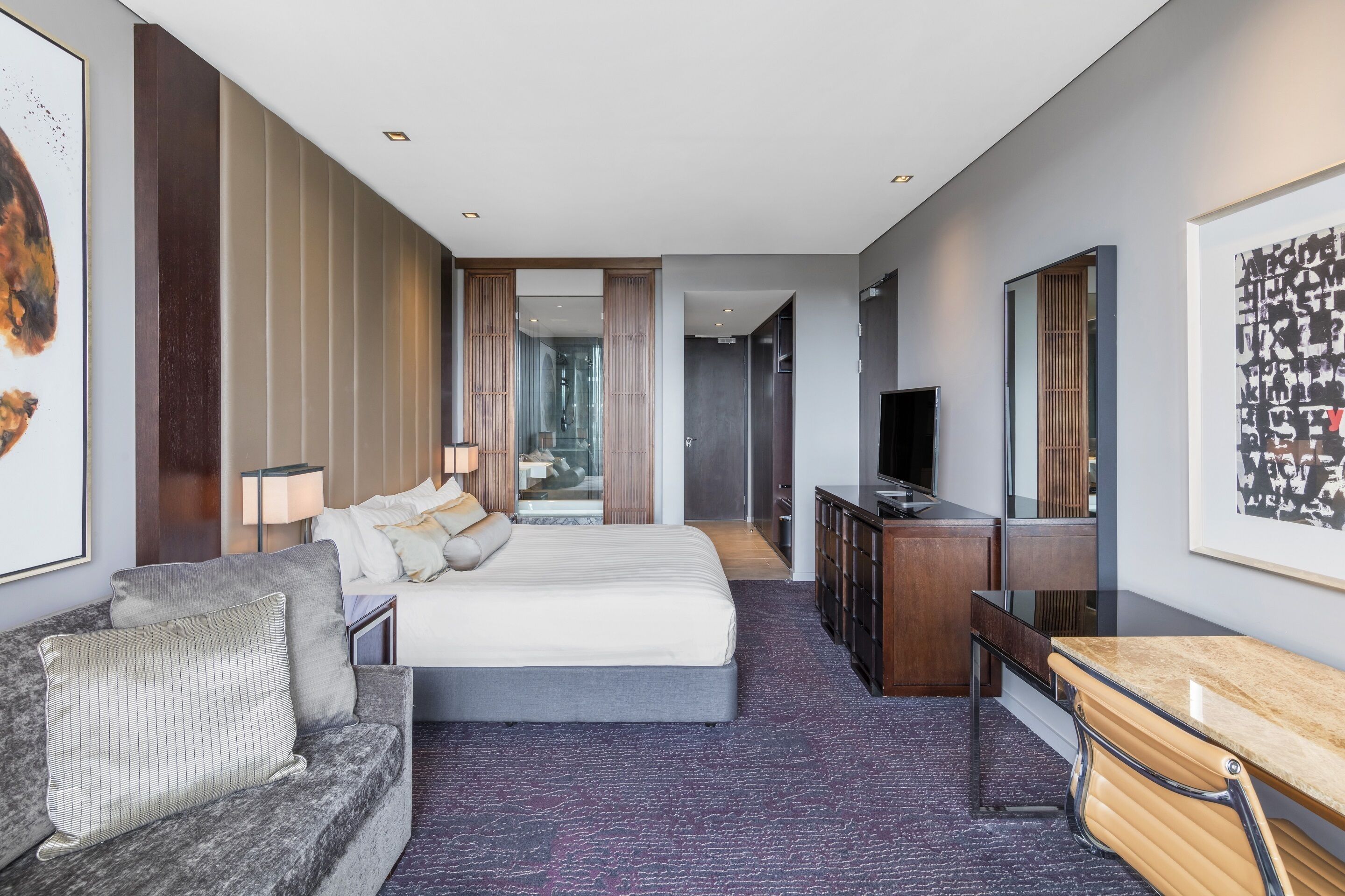 Una camera d'albergo moderna con un letto grande, una scrivania, una TV e un'area salotto.