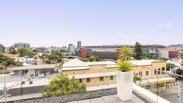 Terraço no terraço com vista para a paisagem urbana, incluindo edifícios e um estádio.