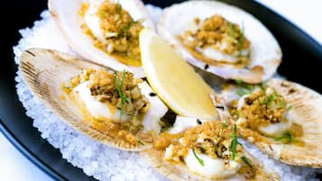 Four scallops on a bed of ice with a lemon wedge.