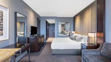 Ein modernes Hotelzimmer mit einem großen Bett, einem Schreibtisch, einem Fernseher und einer Sitzecke.