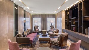 A modern lounge area with a sofa set, armchairs, a coffee table, and a bookshelf. - The Beetson Hotel (Petrie Terrace)