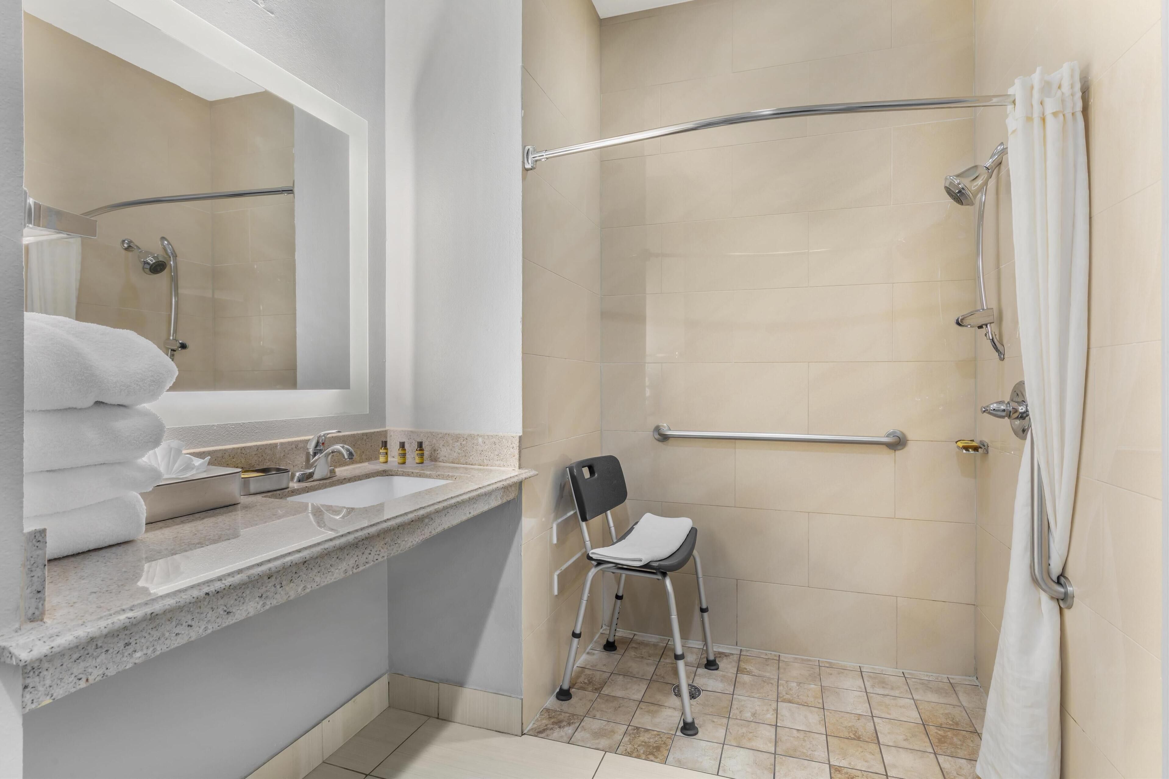 Un baño con lavamanos, espejo y ducha.