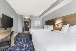 Ein Hotelzimmer mit Bett, Schreibtisch mit Stuhl, Fernseher und Wandleuchte.