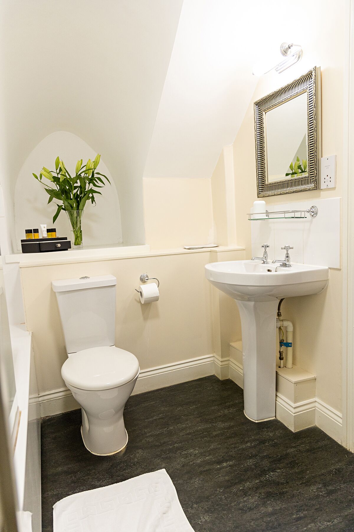 A bathroom with a toilet, sink, and mirror.