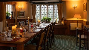 A dining room with a long wooden table set for a meal, surrounded by chairs. - The Royal Oak Exmoor (Minehead)