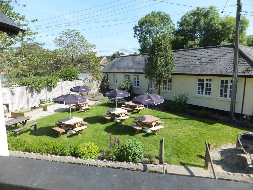 A courtyard with picnic tables and umbrellas, surrounded by a building with a sloped roof.