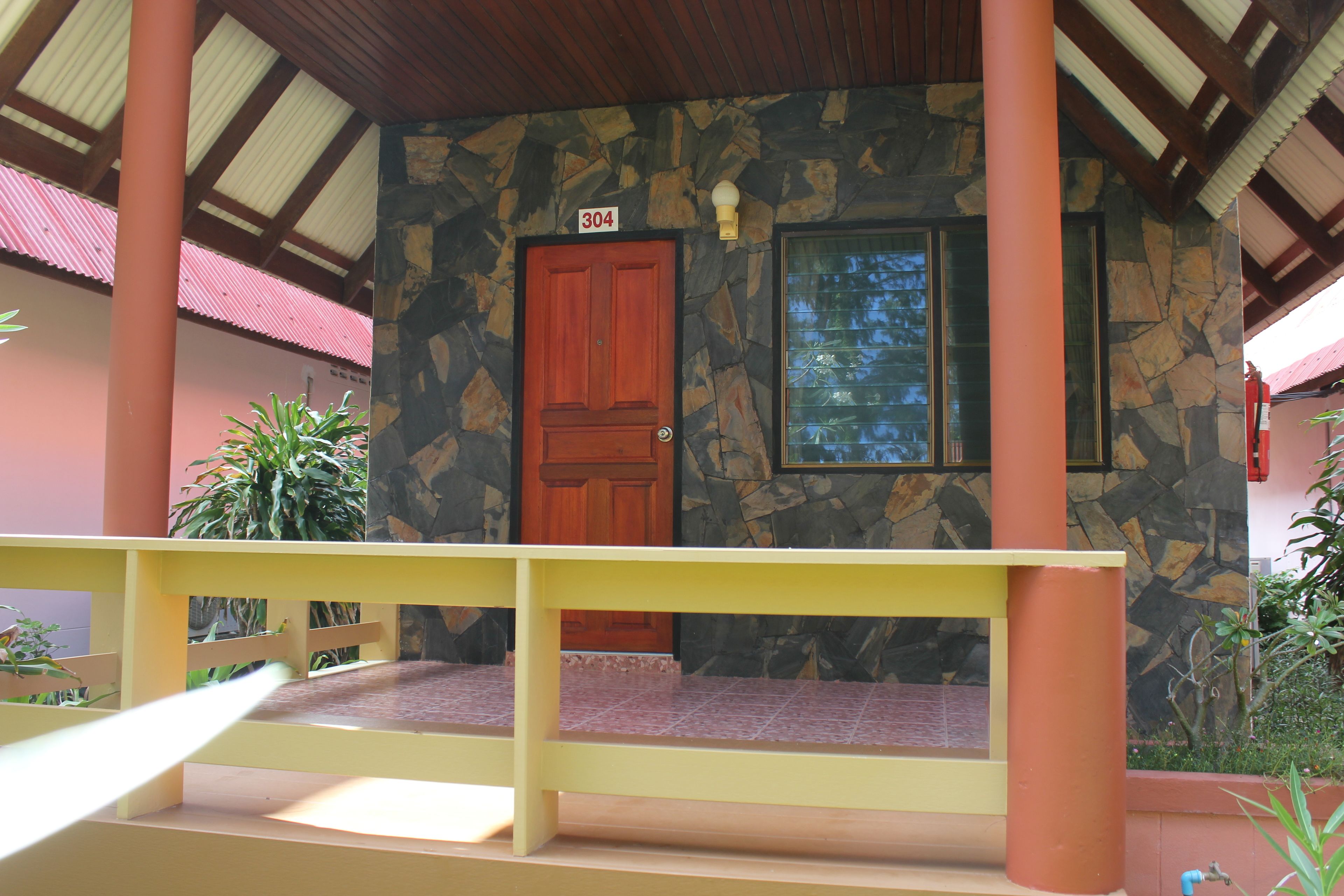 A building with a stone facade, a wooden door with the number 304, and a yellow railing.