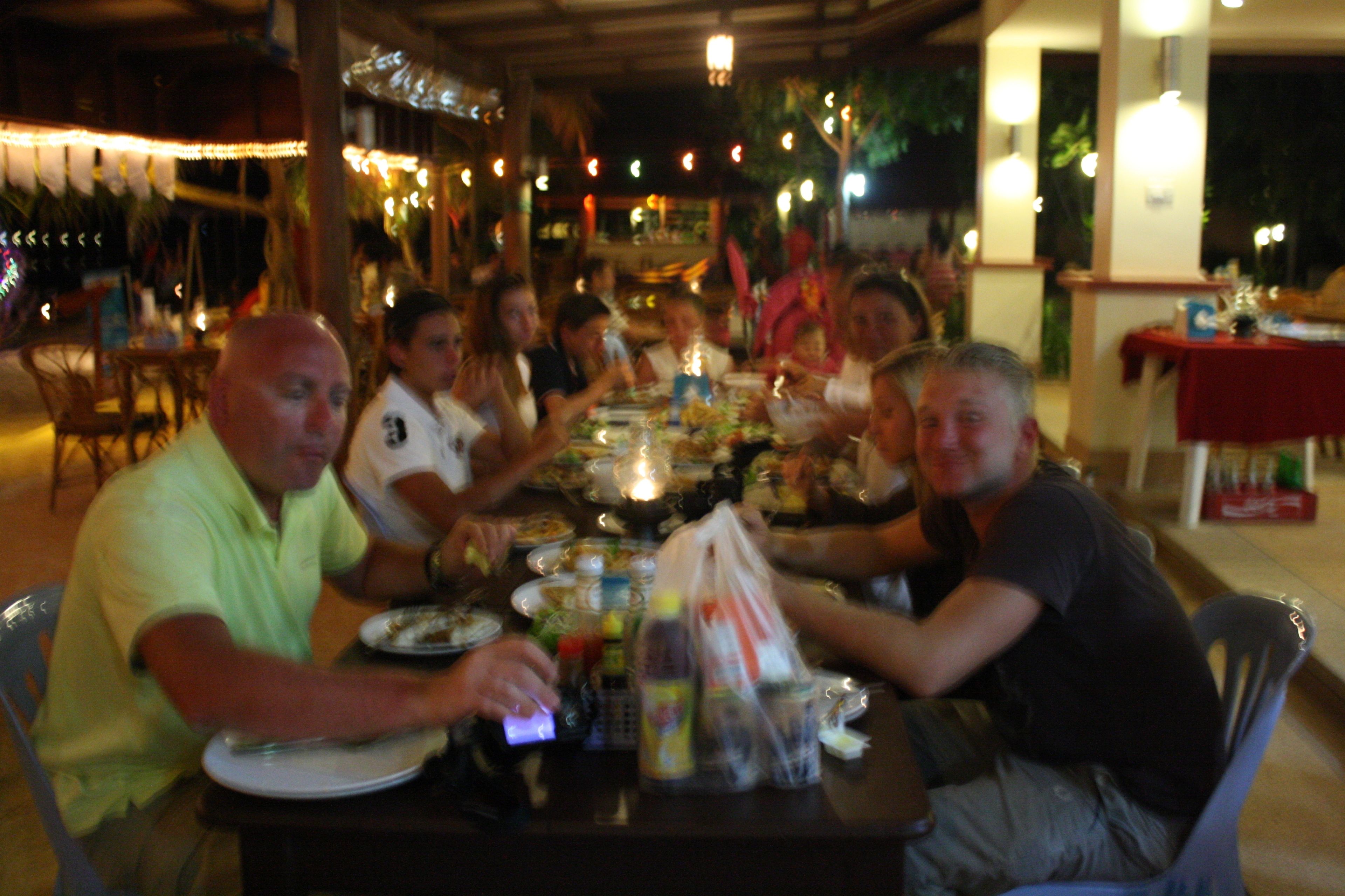A group of people dining at an outdoor restaurant with tables set for meals.