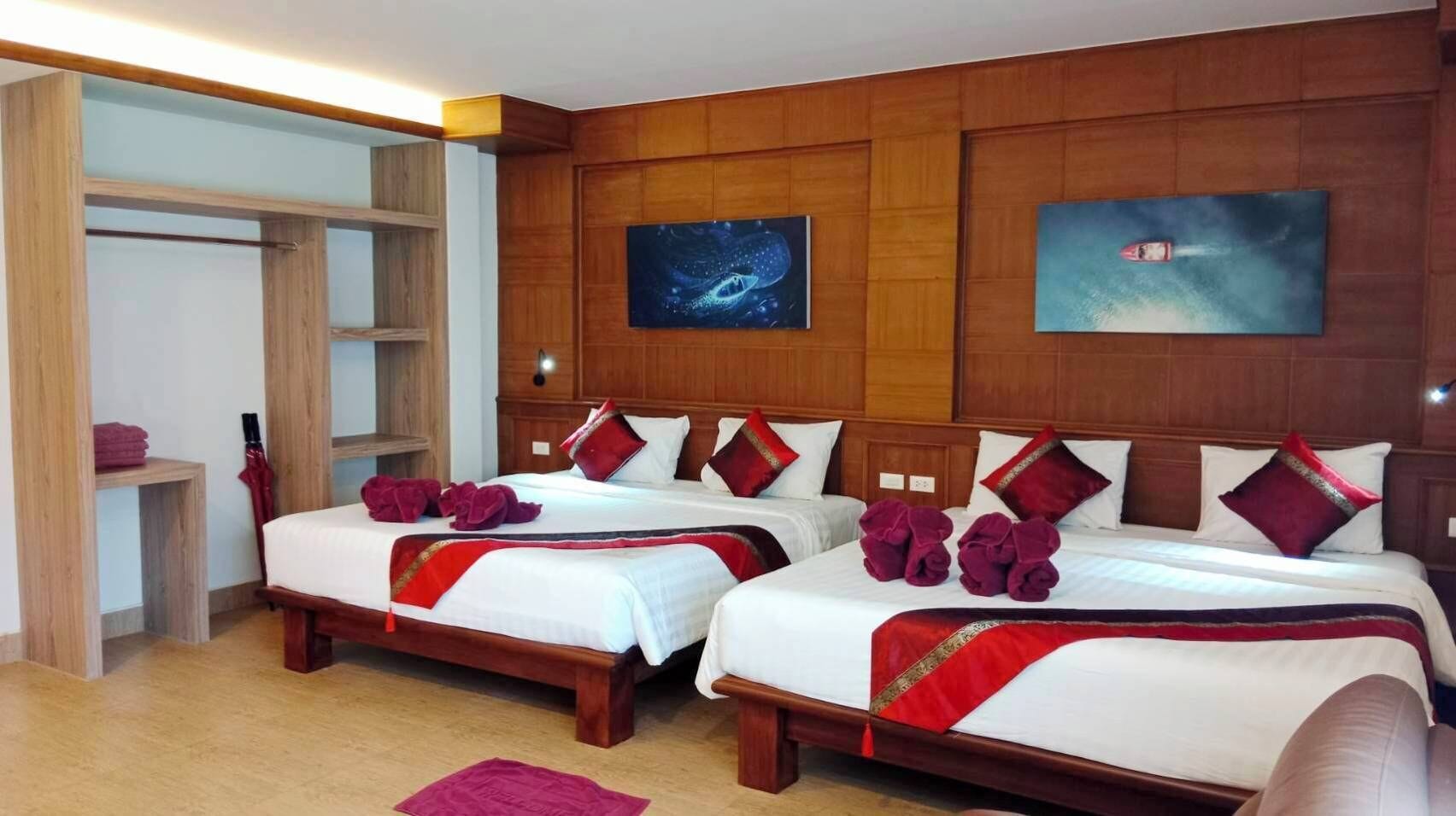 A hotel room with two beds, wooden headboards, a wardrobe, and artwork on the walls.