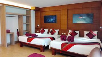 A hotel room with two beds, wooden headboards, a wardrobe, and artwork on the walls.