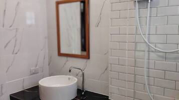 A bathroom with a white marble sink, black countertop, and a mirror.