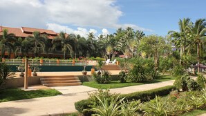 Un resort con piscina, palme e cielo sereno.