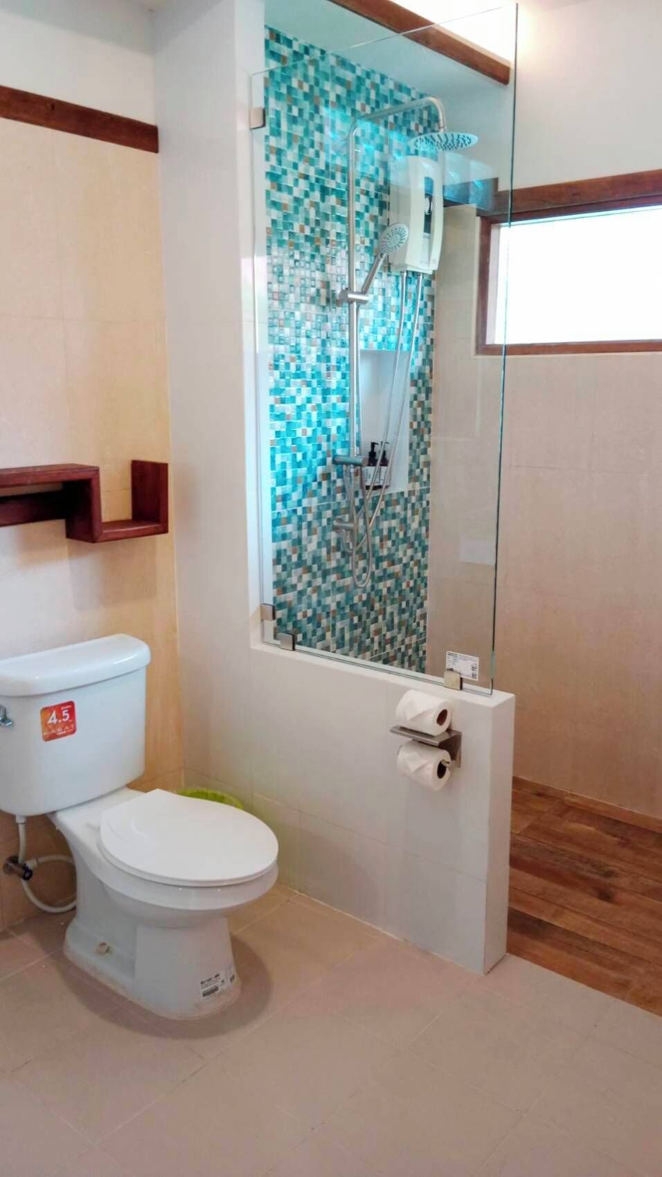 A bathroom with a toilet, a shower with a glass enclosure, and a tiled wall.