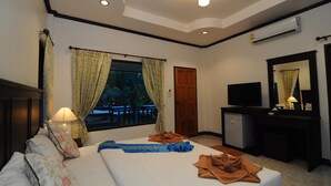 Une chambre d’hôtel avec un lit, un bureau, une télévision et une fenêtre avec des rideaux.