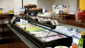 Een buffet met diverse gerechtjes, waaronder fruit, vleeswaren en sauzen.