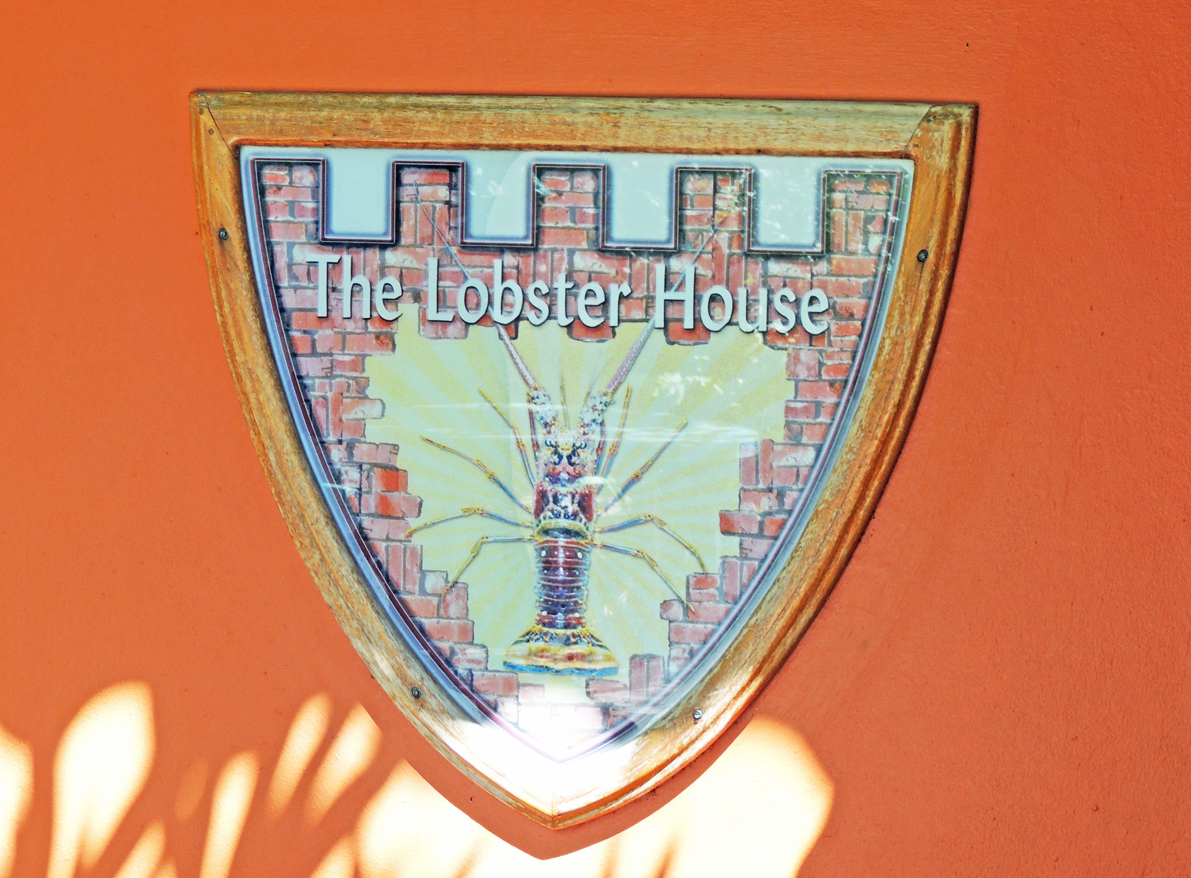 Un letrero con forma de escudo que muestra el texto 'The Lobster House' e una ilustración de langosta.