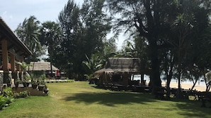 A well-maintained grassy area with a concrete pathway leading to a thatched-roof structure. - Good Days Lanta Beach Resort (Ko Lanta)