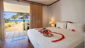 A hotel room with a bed, a nightstand, a lamp, and a view of a beach. - Good Days Lanta Beach Resort (Ko Lanta)