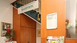 Un área de recepción con un mostrador de madera, un letrero encima y un cuadro en la pared.