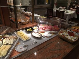 Un bufé con diversas opciones de comida, incluyendo quesos, carnes y frutas.