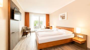 Una habitación de hotel con una cama de madera, un escritorio, una silla, un televisor y una ventana con cortinas.